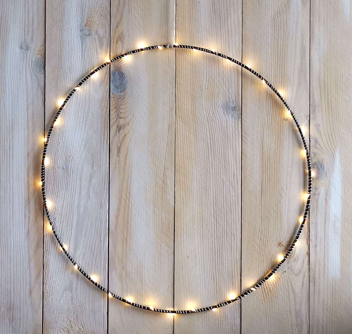 Beleuchteter großer Metallring mit einer LED Lichterkette als Fensterdekoration in der Weihnachtszeit